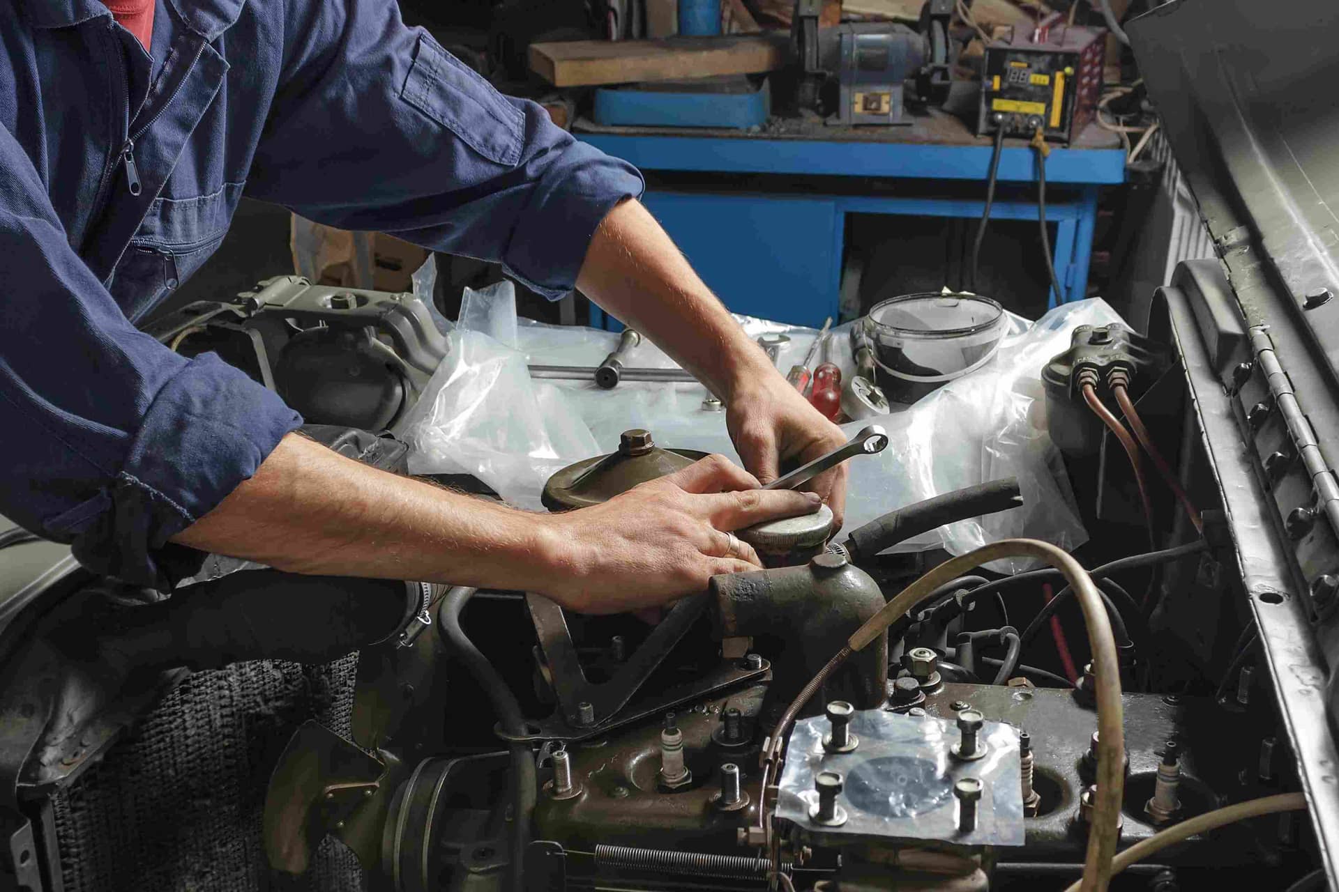 Auto mechanic working under the hood of an old car engine. Auto mechanic working under the hood of an old car engine.